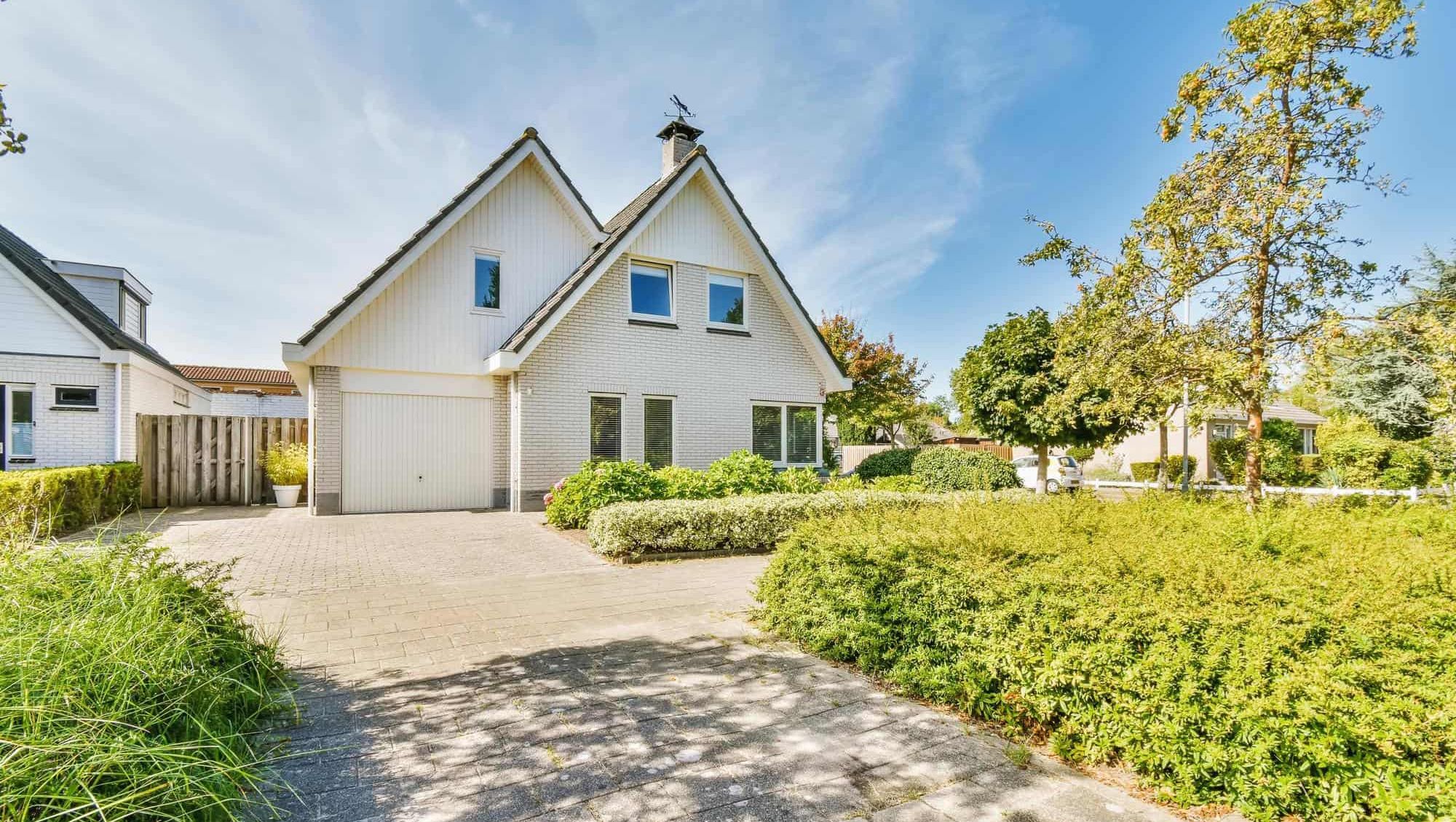 Moderne enebolig med hage og innkjørsel under blå himmel.